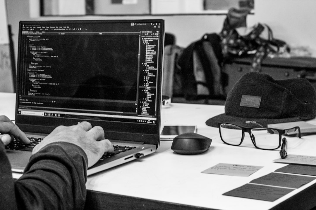 foto em preto e branco de um homem usando laptop codificando